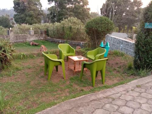 four green chairs and a table in a yard at Bruton resorts in Kodaikānāl