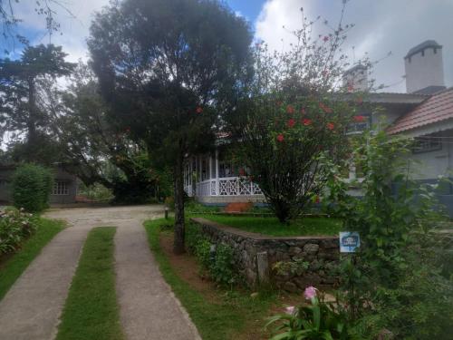 a house with a fence and a tree with red flowers at Bruton resorts in Kodaikānāl