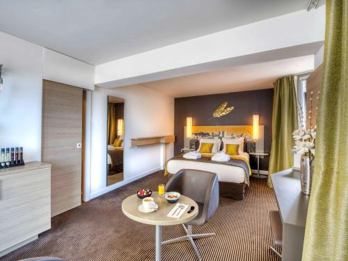 a hotel room with a king sized bed and a table at Mercure Avignon Centre Palais des Papes in Avignon