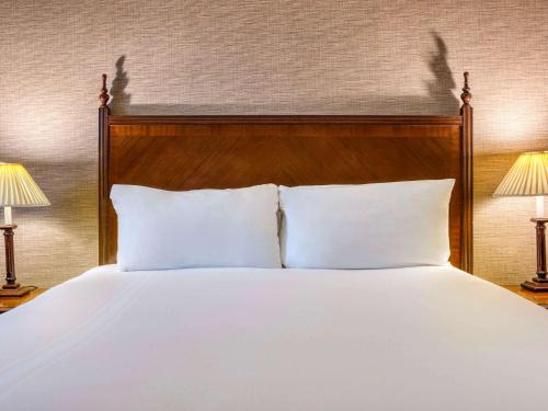a bed with white pillows and two lamps at Winchester Wessex Hotel by Sunday in Winchester