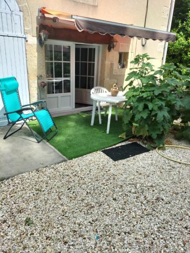 a patio with a table and a chair on the grass at Chambre de caractere in Celles