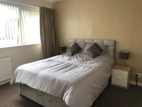 a bedroom with a white bed with pillows and a window at Ainsdale Gardens in Birmingham