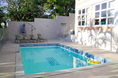 a swimming pool with chairs next to a building at Pousada Pomar De Manguinhos in Manguinhos