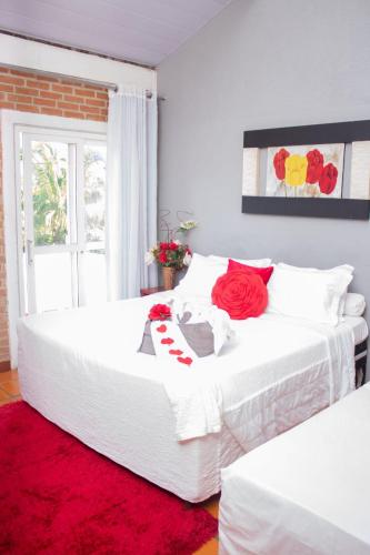a bedroom with two white beds with a red rug at Pousada Pomar De Manguinhos in Manguinhos