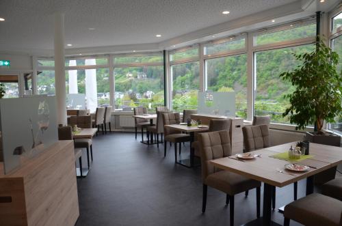 a restaurant with tables and chairs and windows at Flair Hotel am Rosenhügel - Garni in Cochem