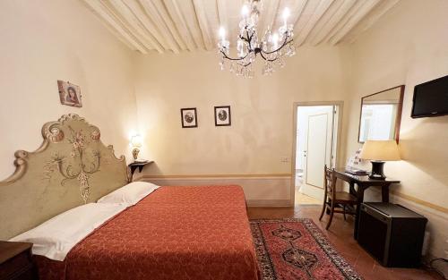 a hotel room with a bed, table, lamp, mirror and window at Hotel San Michele in Cortona