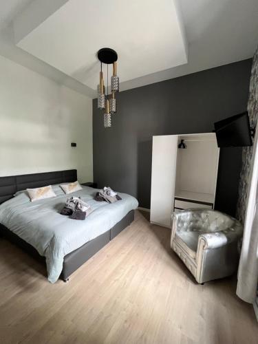 Un dormitorio con una cama grande y una lámpara de araña. en L'heure de la détente Spa privatif, en Beauraing