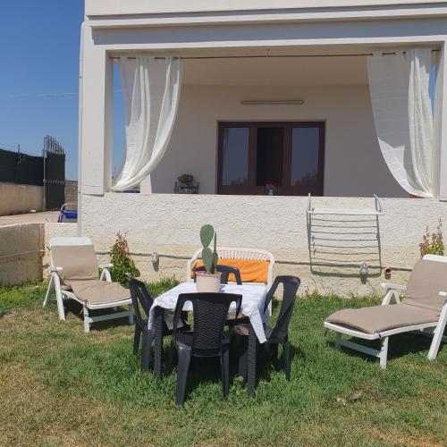 een tafel met stoelen en een vaas erop bij villetta immersa nell'agrumeto in Noto Marina