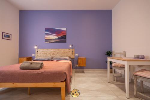 a bedroom with purple walls and a bed with a table at Pesce Palla Affittacamere in Finale Ligure