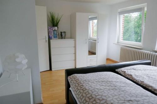 a bedroom with a bed and a dresser and two windows at FerieninNordhorn in Nordhorn