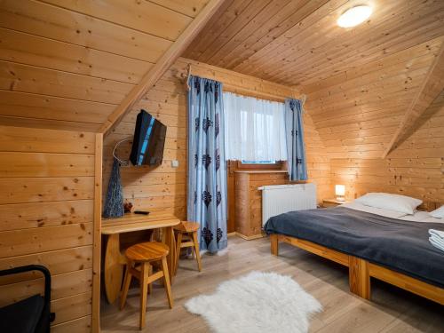 ein Schlafzimmer in einem Blockhaus mit einem Bett und einem Schreibtisch in der Unterkunft Domki Na Babińcu in Zakopane