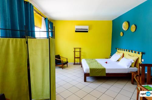 Schlafzimmer mit einem Bett und gelben und blauen Wänden in der Unterkunft Hôtel Restaurant Coco Lodge Majunga in Mahajanga