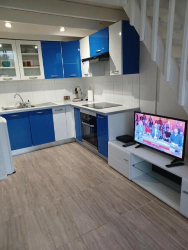 a kitchen with blue cabinets and a flat screen tv at Résidence MARINA 3 in Les Trois-Îlets