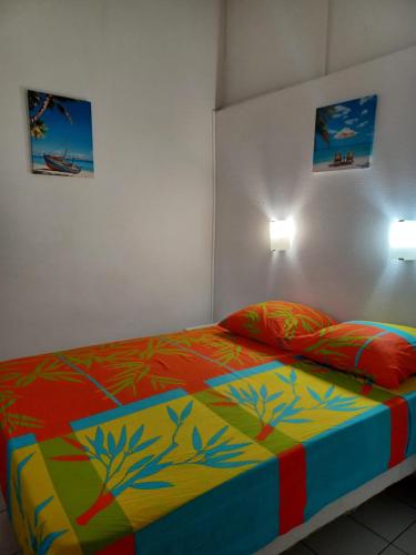 a bedroom with a bed with a colorful comforter at Résidence MARINA 3 in Les Trois-Îlets