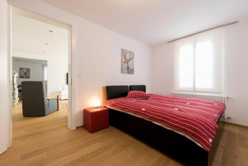 a bedroom with a large bed with a red blanket at Zer Treichi Appartements in Fiesch