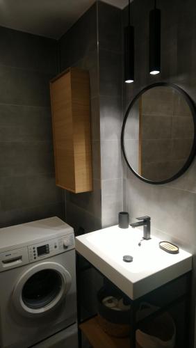 een badkamer met een wastafel en een wasmachine bij Maja Apartment in Sopot