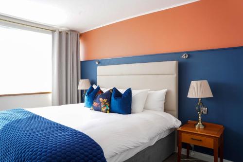 a blue bedroom with a bed with blue and orange walls at Alcock & Brown Hotel in Clifden