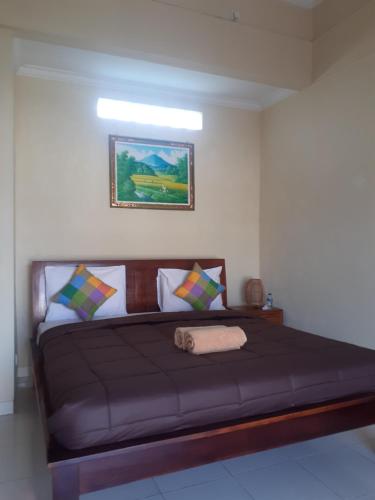 a bedroom with a large bed with a brown bedspread at Nami House in Ubud