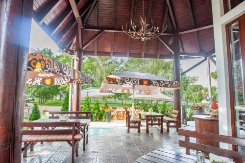 a restaurant with wooden tables and benches and a chandelier at Penzión Tücsök in Šamorín