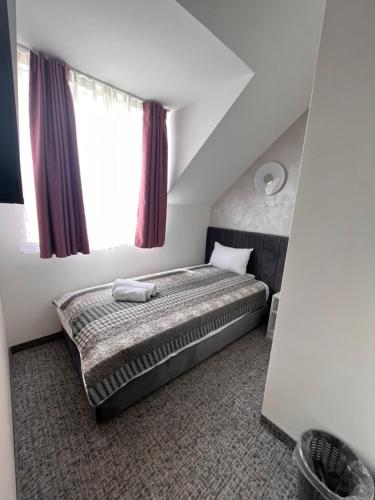 a small bedroom with a bed with a window at Navigator in Palić