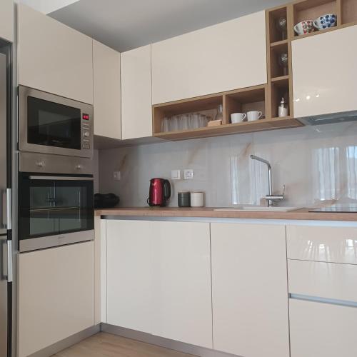 a kitchen with white cabinets and a microwave at Anesi View Apartment in Vasiliki