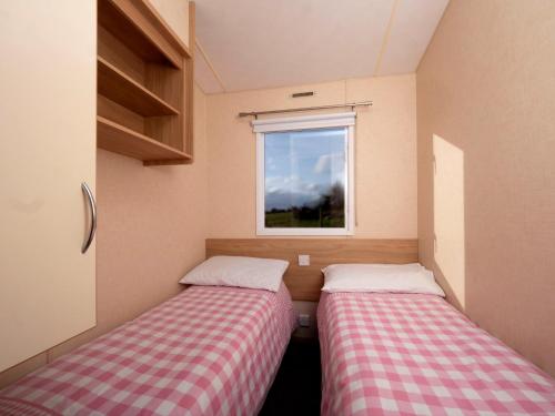 two beds in a small room with a window at Crockgarve B and B in Galbally