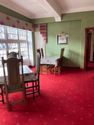 a dining room with a table and chairs and windows at The Panmure Arms Hotel in Edzell