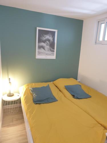 a bedroom with a yellow bed with a picture on the wall at Le Drellac'h in Le Conquet