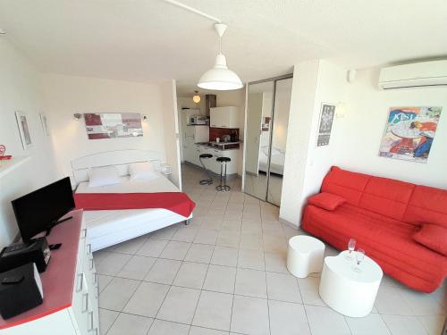 une chambre avec un lit et un canapé rouge dans l'établissement Studio Village Naturiste Carino, au Cap d'Agde