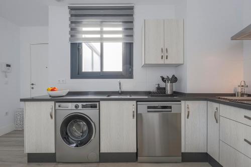 a kitchen with a washing machine and a sink at Family HOME SUITS Encantos de Sevilla in Seville