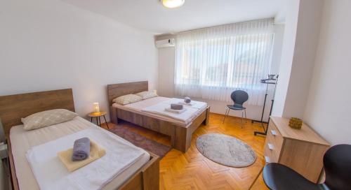 Habitación con 2 camas, mesa y ventana en Apartment Revia, en Mostar