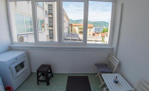 Habitación con 2 sillas y 2 ventanas. en Apartment Revia, en Mostar