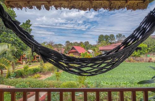 a hammock hanging from a porch with a yard at The Nest House in Pai