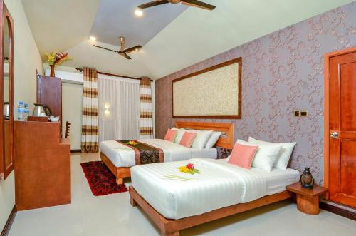 ein Hotelzimmer mit 2 Betten und lila Tapeten in der Unterkunft Maladiwa Beach & Spa in Maafushi