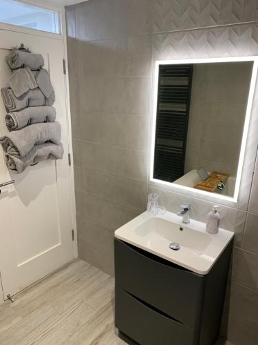 a bathroom with a sink and a mirror and towels at Seaview Aurora House - Central Luxury Apartment in Warrenpoint