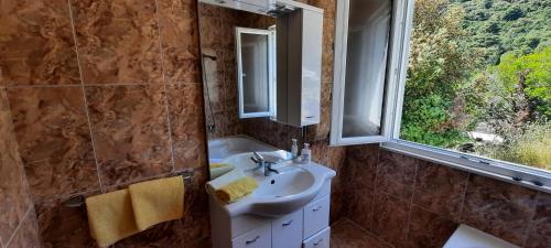 łazienka z umywalką, lustrem i oknem w obiekcie Apartments Lampalo w mieście Okuklje