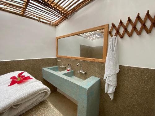 a bathroom with a blue sink and a mirror at Lala Land Lodge in Kizimkazi