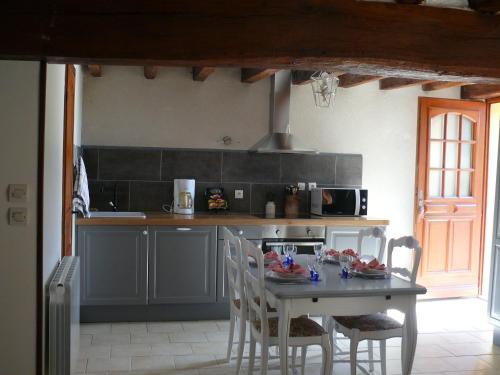 a kitchen with a table and chairs and a counter at Gîtes à l'ombre des chênes in Châteauvieux