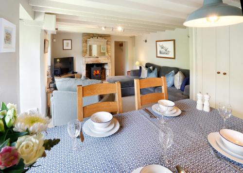 een woonkamer met een tafel met borden erop bij Cosy cottage Blockley, Cotswolds - Squire Cottage in Blockley