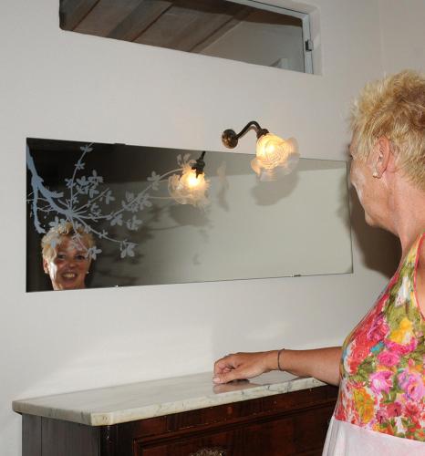 a woman standing in front of a mirror at Apartment La Scala 1572 in San Quirico dʼOrcia