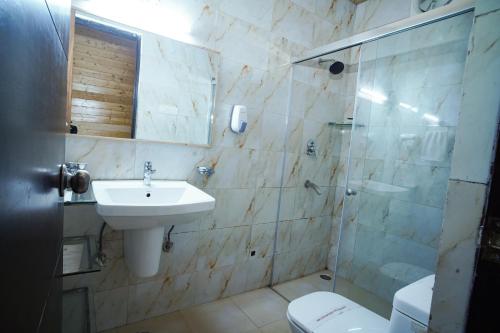 a bathroom with a sink and a shower and a toilet at Comfort Inn Coral River in Mādhopur