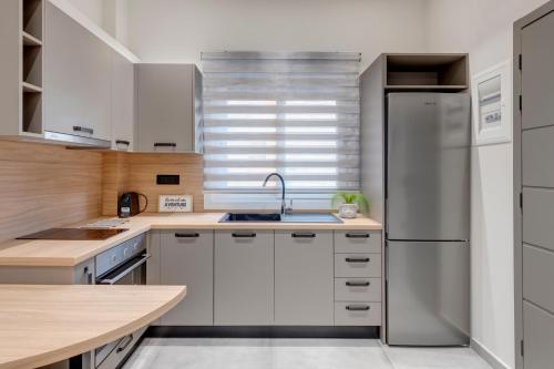 a kitchen with white cabinets and a stainless steel refrigerator at Argento urban apartment (sphere) in Ermoupoli