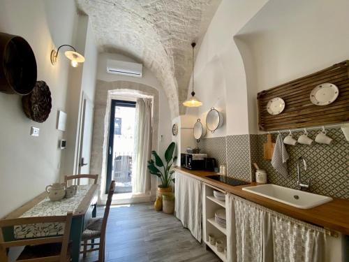 a kitchen with a sink and a counter with a table at La Casetta di Erasmina in Castellana Grotte
