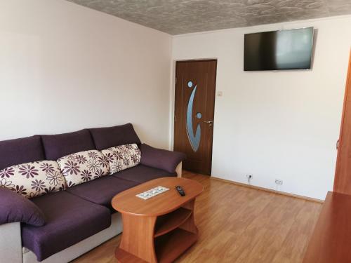 a living room with a purple couch and a table at Apartament Natalie&Helen in Zărneşti