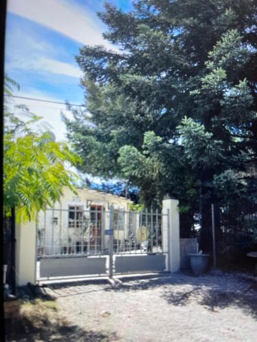 uma cerca em frente a uma casa com uma árvore em Location de vacances (maison) Chez MIMMO em La Verdière