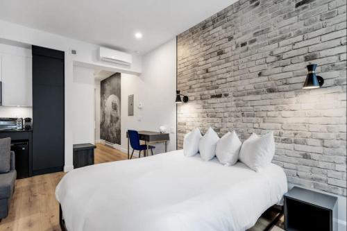 a bedroom with a white bed and a brick wall at INITIAL - ASTRONAUTE - Centre-Ville de Quebec in Quebec City