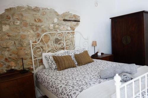 1 dormitorio con cama blanca y pared de piedra en Olive Branch El Chorro, en El Chorro