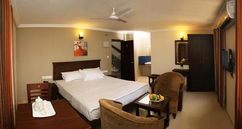 une chambre d'hôtel avec un lit, une table et des chaises dans l'établissement Century Grand Hotel, à Mananthavady