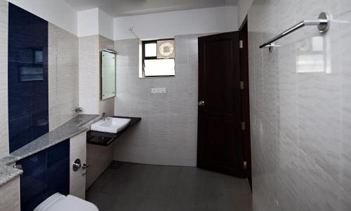 W łazience znajduje się umywalka, toaleta i lustro. w obiekcie Century Grand Hotel w mieście Mananthavady