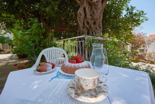 a table with a cup of coffee and strawberries on it at Apartmani Kuća u maslinama in Sveti Stefan